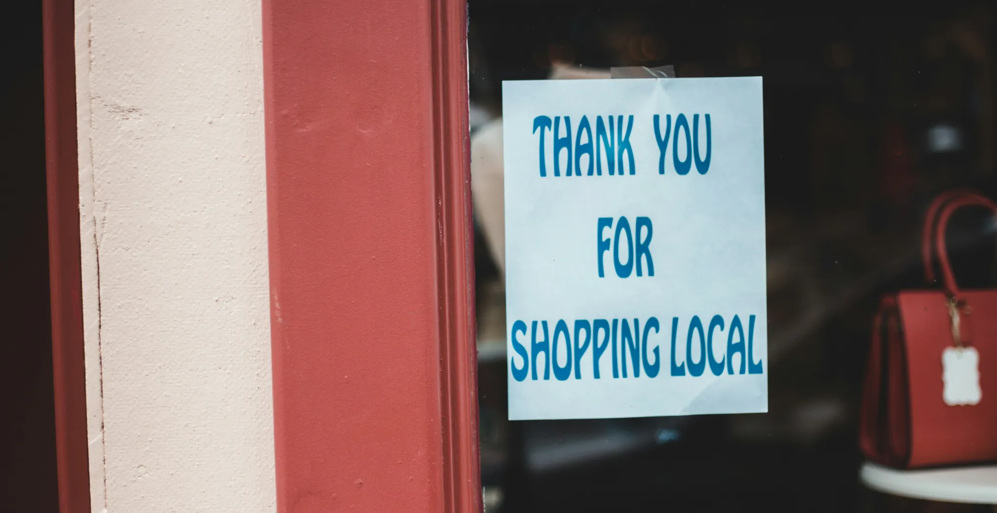 An image showing a shop front with a sign reading 'Thank you for shopping local'.
